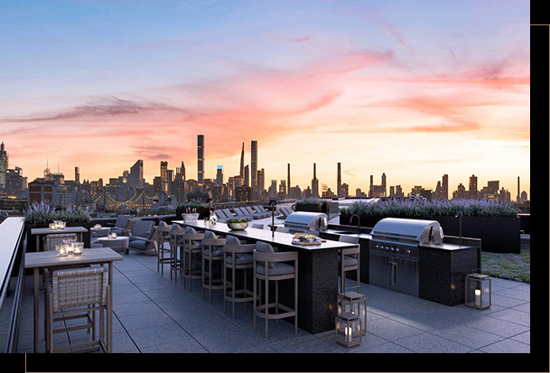 Rooftop at sunset with outdoor grills and kitchen area, ample seating at counter and side tables and city views