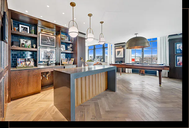Bright bar and billard room with wood flooring, built in shelving with tile backsplash and large windows